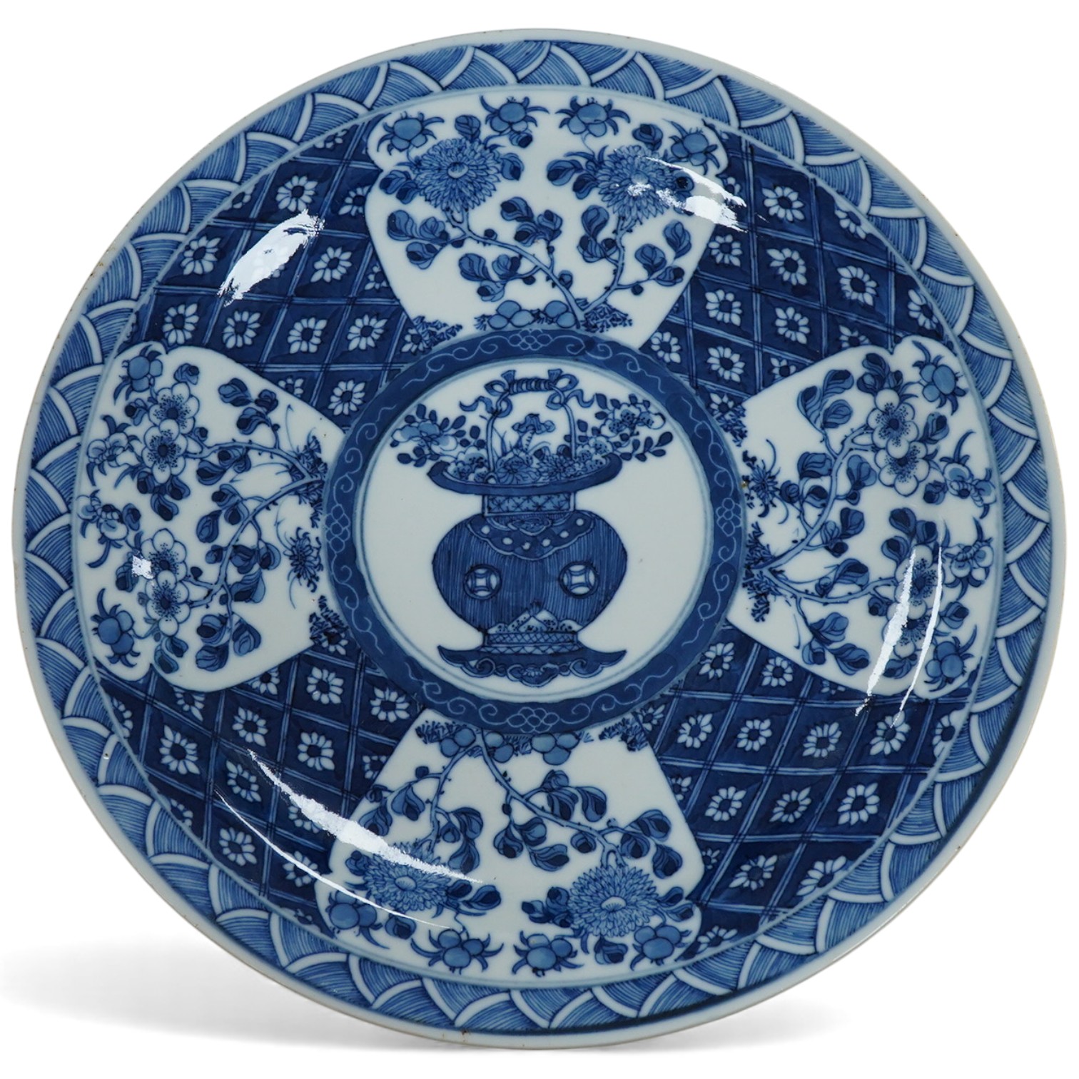 A 19th century Chinese blue and white plate decorated with a flower basket, apocryphal Kangxi four character mark to the base, 25cm in diameter